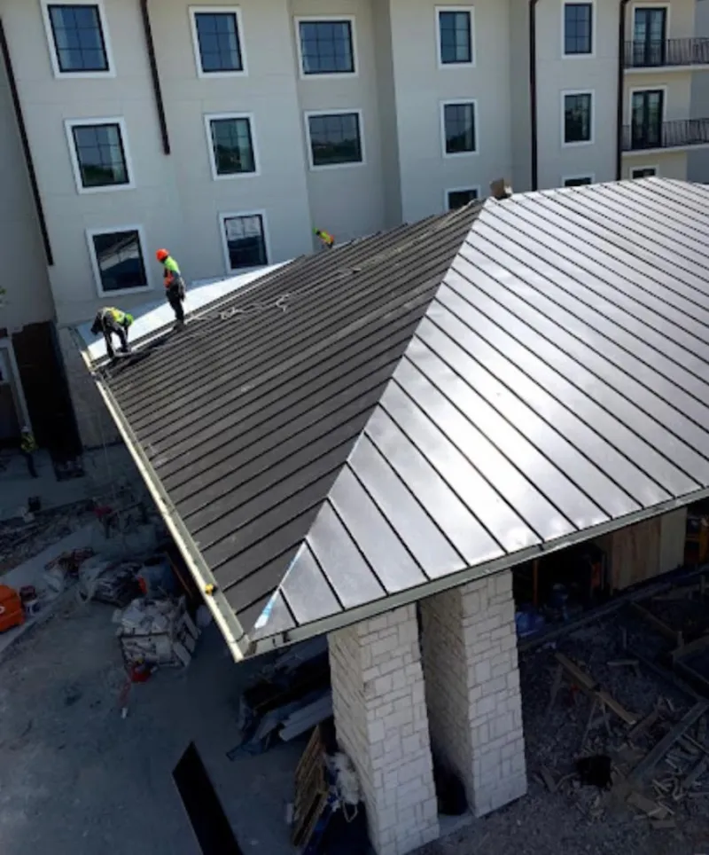 Crew installing standing seam metal roof panels on a commercial project in Mound